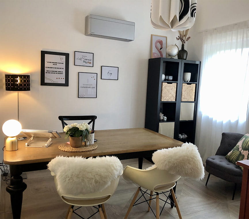 Bureau de Julie Venturini, composé d'une table en bois, deux chaises blanches faisant face à une chaise noire et 4 tableaux accrochés au mur