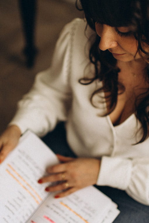 Photo de Julie Venturini prise de haut, elle tient et lit un cahier avec des notes